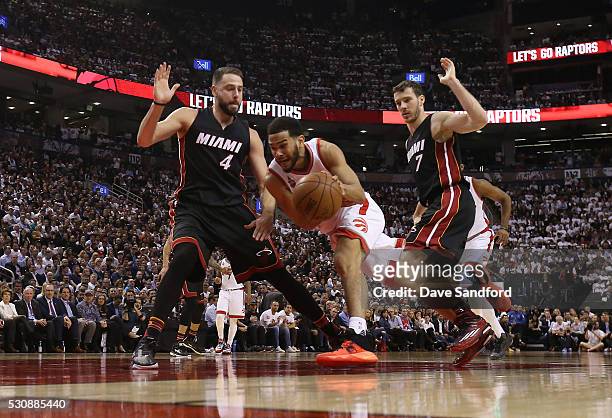 Cory Joseph of the Toronto Raptors drives to the basket as both Josh McRoberts of the Miami Heat and Goran Dragic of the Miami Heat guard against him...