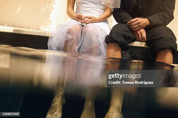 bride and bridegroom sitting with feet in water - bride underwater stock pictures, royalty-free photos & images