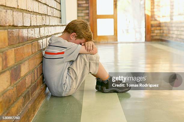 sad schoolboy sitting in the hallway - school punishment stockfoto's en -beelden