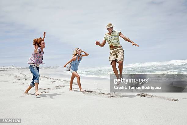 friends on beach - junge frau strand sand springen stock-fotos und bilder