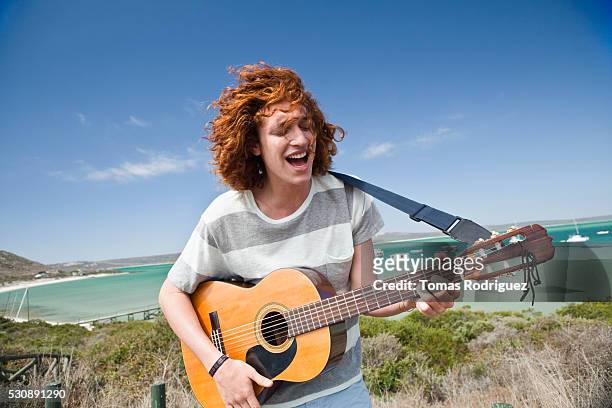 man playing guitar outdoors - wind instruments stock-fotos und bilder