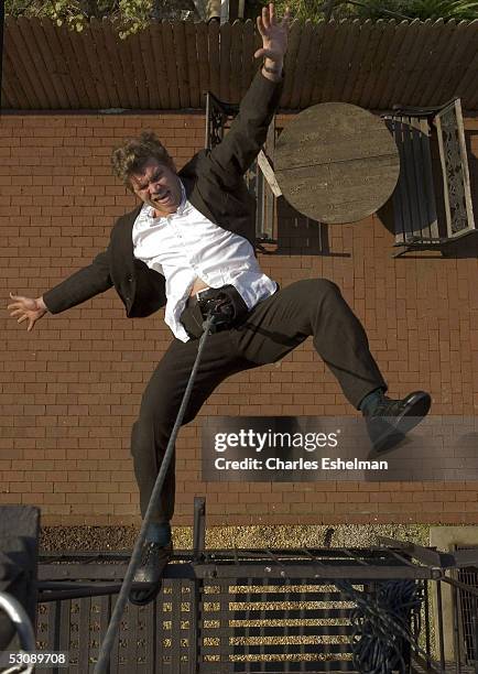 Performance artist Kerry Skarbakka, 34-years-old, gestures as he hangs from his fire escape by rope and harness at his studio May 14, 2005 in the...