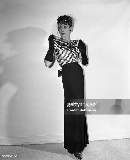 An eye-catching bodice of black and pink striped satin, embroidered with jet, tops the slim black crepe skirt of this Hattie Carnegie model. The...