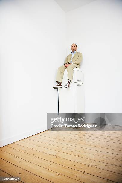 man sitting on top of refrigerator - funny fridge stock pictures, royalty-free photos & images