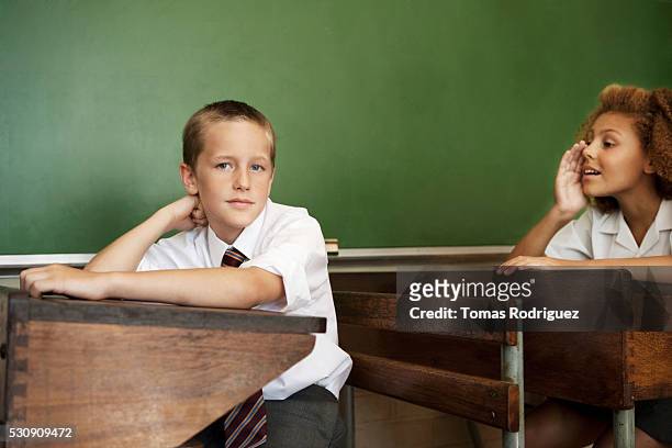 students whispering in class - school tie stockfoto's en -beelden