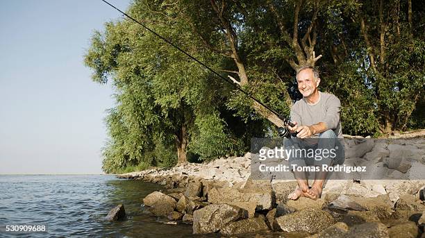 man fishing by river - season 61 stock pictures, royalty-free photos & images
