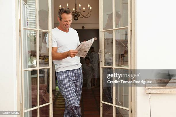 man reading newspaper - schlafanzug stock-fotos und bilder