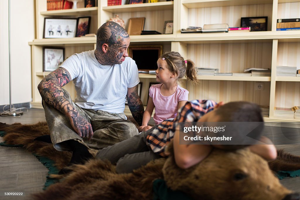 Father and daughter sitting on bear skin rug and communicating.
