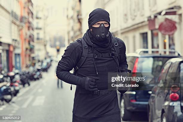 male jogging in black in paris street wearing breathing apparatus - counter terrorism stockfoto's en -beelden