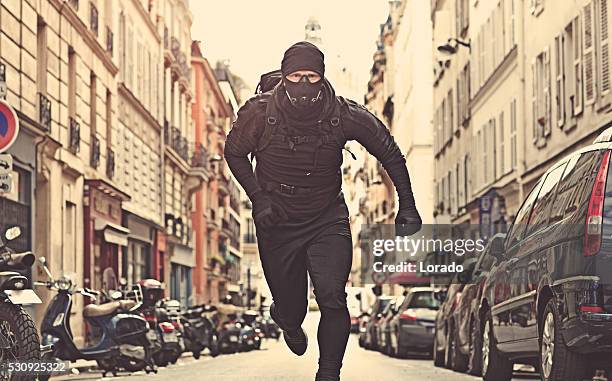 male jogging in black in paris street wearing breathing apparatus - street villains stock pictures, royalty-free photos & images