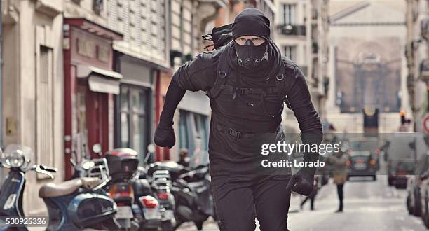 male jogging in black in paris street wearing breathing apparatus - street villains stock pictures, royalty-free photos & images