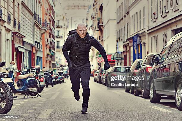 bald white male jogging in black in paris street - special force stock pictures, royalty-free photos & images