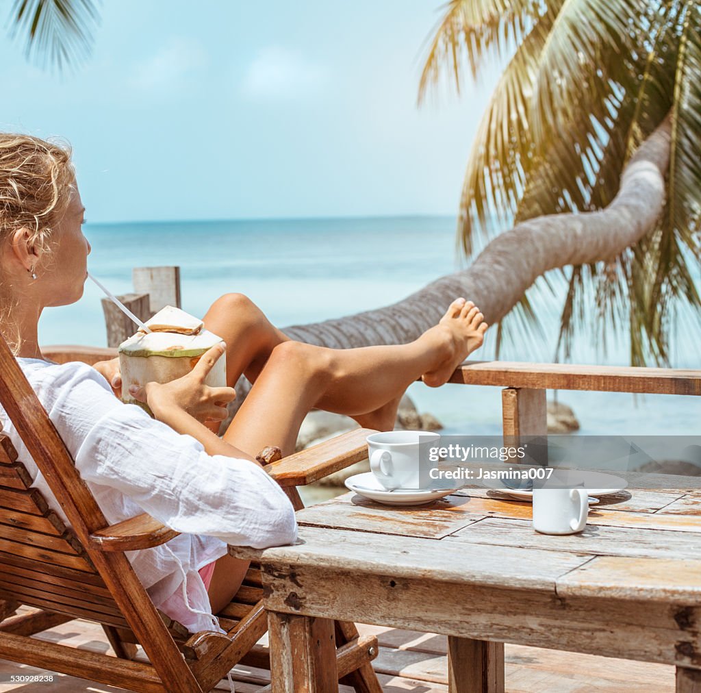 Young woman enjoys drinking coffee and coconut