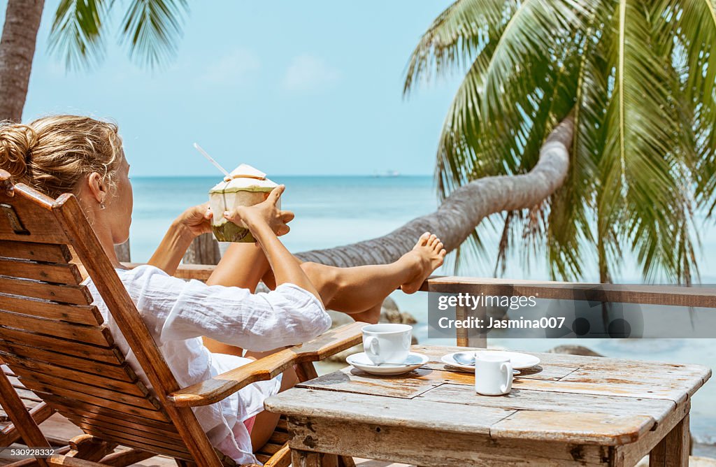 Mujer joven bebiendo café y coco ofrece