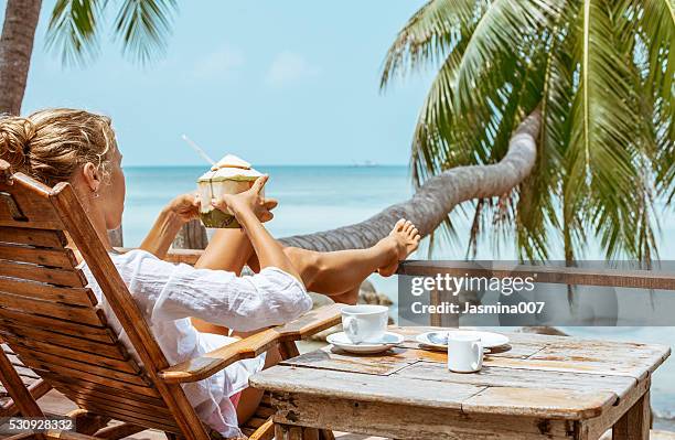 young woman enjoys drinking coffee and coconut - coconut beach woman stock pictures, royalty-free photos & images