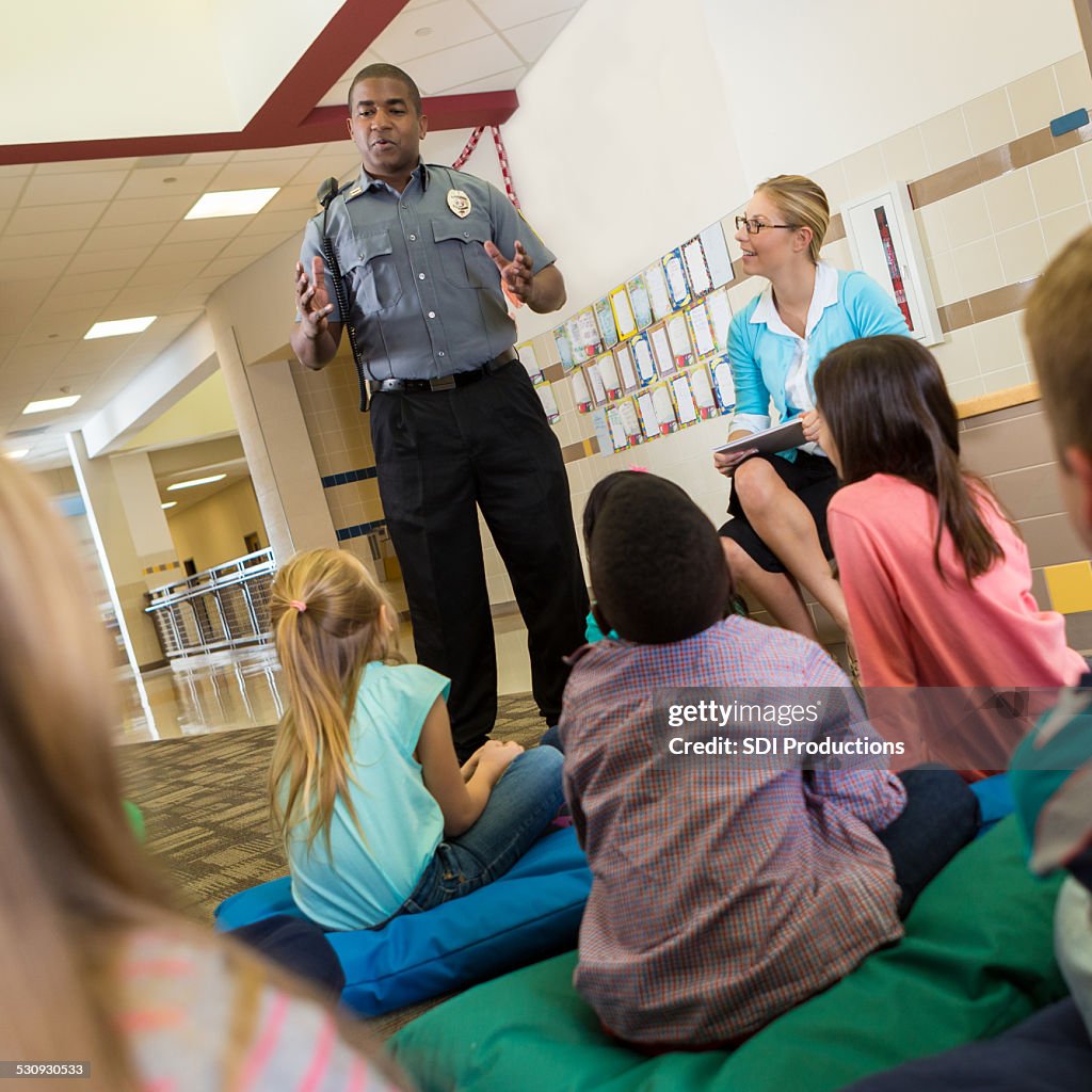 Police Officer At School Speaking To Young Students About Safety High