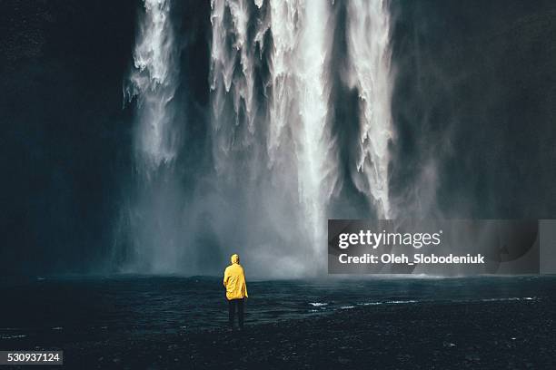man near the waterfall - iceland cave stock pictures, royalty-free photos & images
