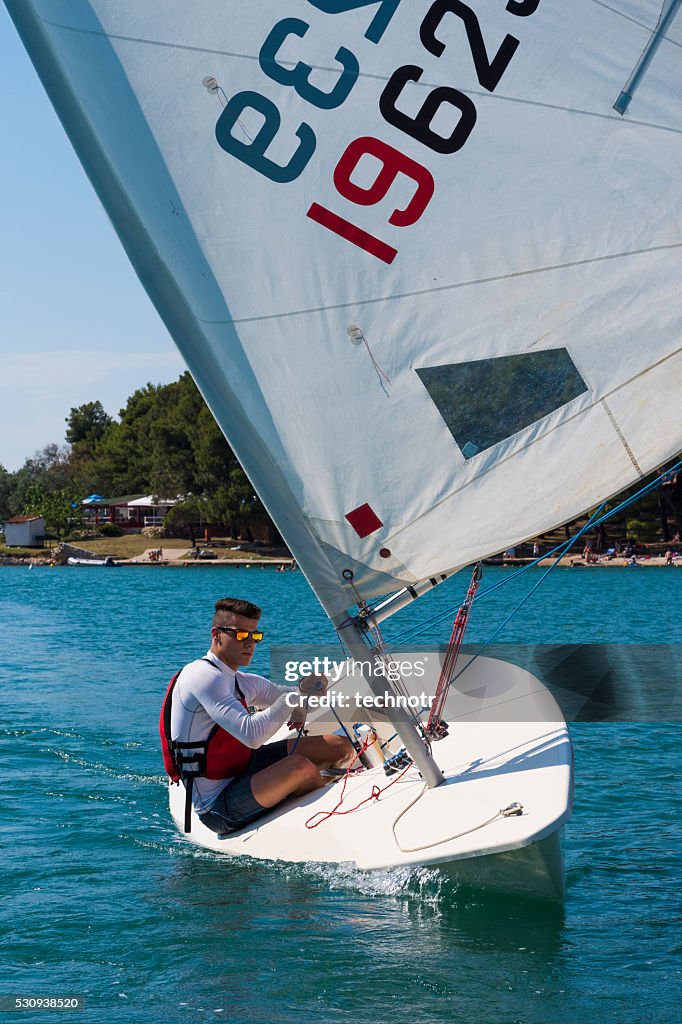 Frente vista de hombre joven sails embarcación Clase de láser