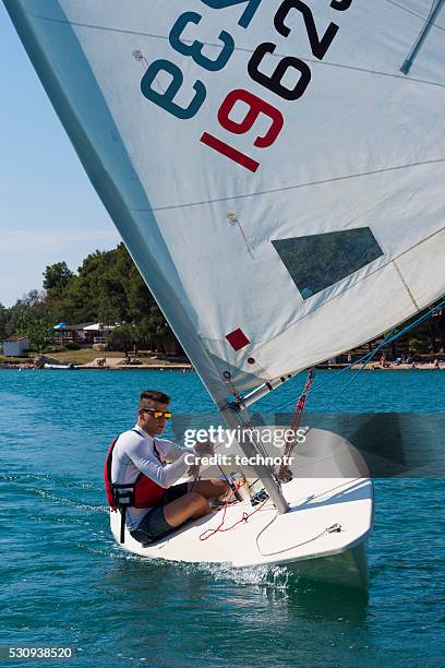 front view of young man sails laser class sailing boat - sailing dinghy stock pictures, royalty-free photos & images