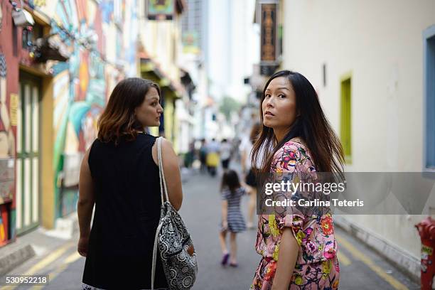 two women walking down singapore's colourful haji lane - singapore alley stock pictures, royalty-free photos & images