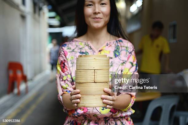 trendy chinese woman holding a stack of dim sum baskets in an ally restaurant - singapore alley stock pictures, royalty-free photos & images