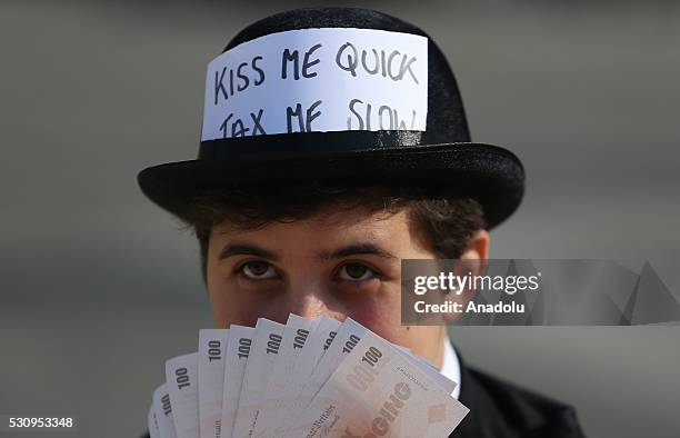 Protester holds fake money during a protest to demonstrate against tax havens at Trafalgar Square during the Global Anti-corruption Summit in London,...