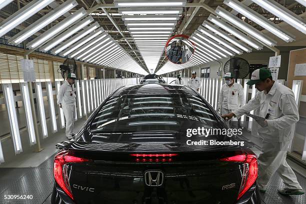 Employees check Honda Civic vehicles at the quality control station on the production line of the Honda Motor Co. Assembly plant in Prachinburi,...