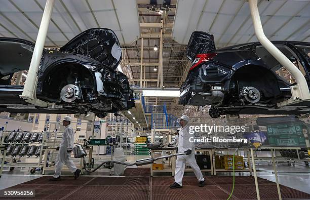 Employees carry an exhaust pipe as they work on the production line of the Honda Motor Co. Assembly plant in Prachinburi, Thailand, on Thursday, May...