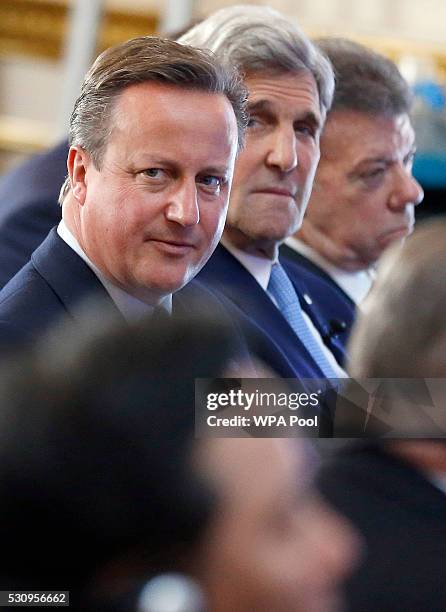 British Prime Minister David Cameron sits beside U.S. Secretary of State John Kerry as they listen during a panel discussion at the international...