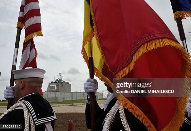Army servicemen carry flags during the inauguration ceremony of the Aegis Ashore Romania facility at the Deveselu military base on May 12, 2016. The...