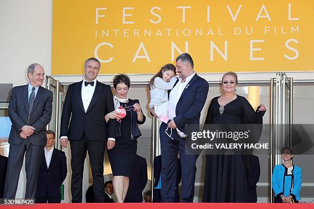 Romanian director Cristi Puiu carries on May 12, 2016 his daughter Romanian actress Zoe Puiu while posing with the President of the Cannes Film...