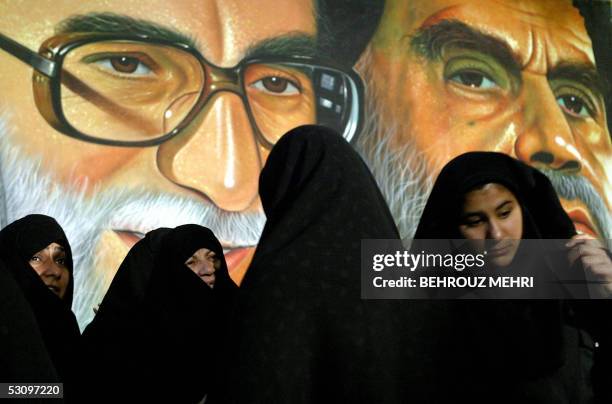 Iranian women wearing black Chador queue up to vote for the presidential elections in front of a portrait of Iran's supreme leader, Ayatollah Ali...