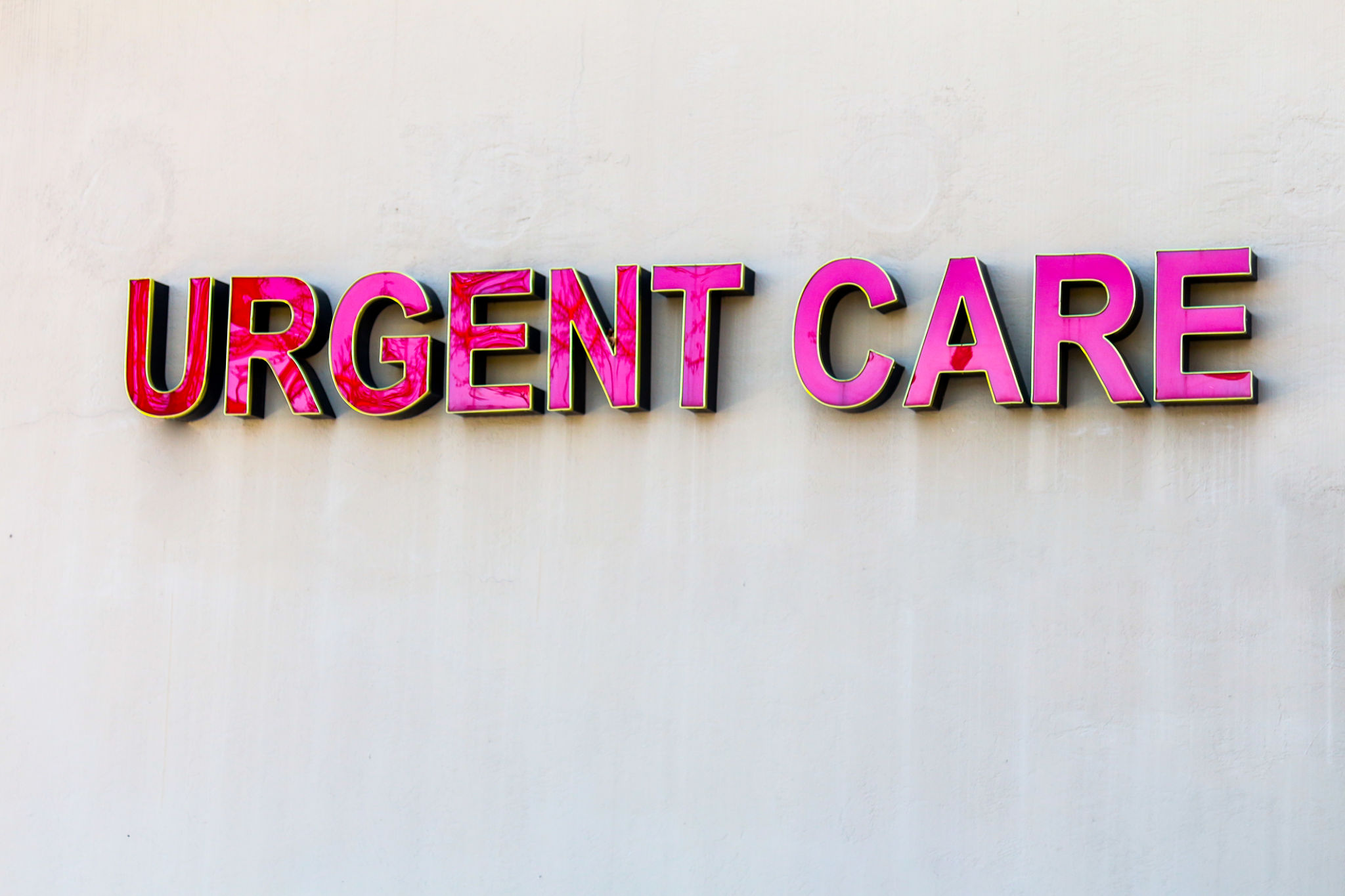 Red urgent care sign on beige wall Red urgent care sign on beige wall
