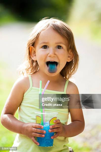 happy messy little girl sticking out blue tongue - happy dirty child stockfoto's en -beelden
