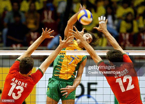 Brazil's Gilberto Godoy spikes the ball before Portugal's Andre Lopes and Joao Jose during their World League 2005 match 18 June, 2005 in Brasilia....