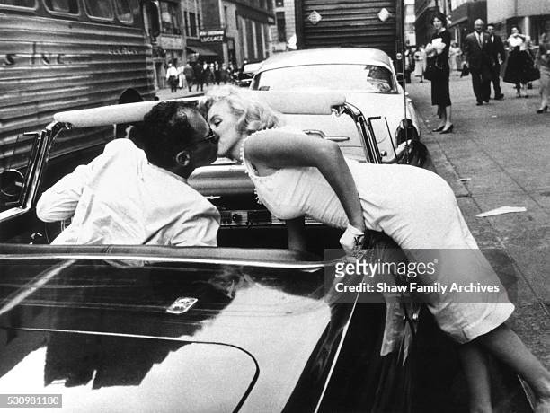 Marilyn Monroe leans over the door of a convertible Ford Thunderbird to kiss her husband, the playwright Arthur Miller, in 1957 in New York, New York.