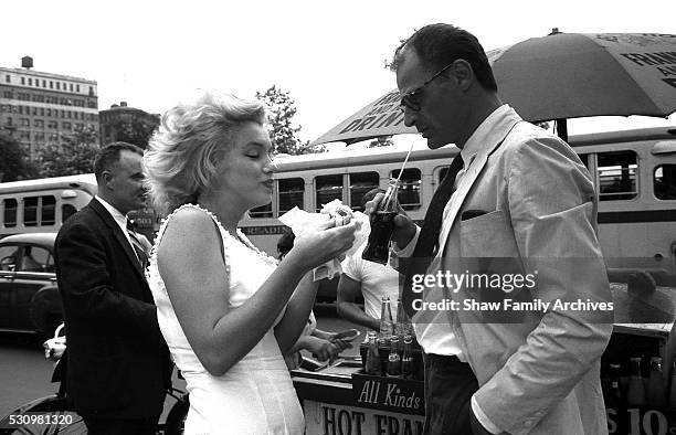 Marilyn Monroe eats a hot dog from a stand with her husband, the playwright Arthur Miller, in 1957 in New York, New York.