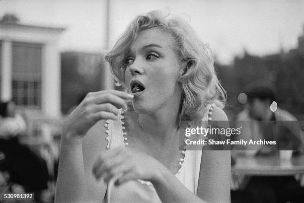 Marilyn Monroe eats a hot dog at an outdoor table in 1957 in New York, New York.