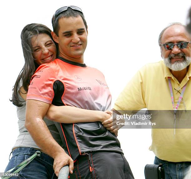 Conny Montoya embrace her husband Juan Pablo Montoya of Columbia and McLaren Mercedes as his father Pablo looks on in the paddock after the...