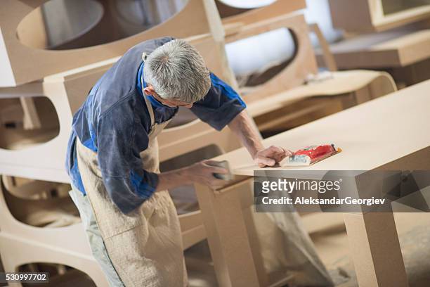 carpentiere operaio invia un tavolo di legno con levigatrice - furniture maker foto e immagini stock