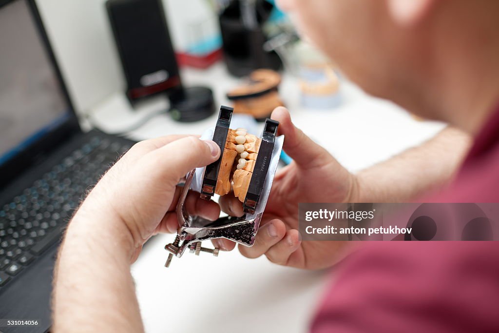 Dental technician working with articulator in dental laboratory