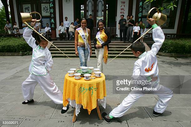 Contestants of 2005 Miss Tourism Queen International, Miss Jamaica and Miss Sri Lanka watch Chinese children to perform pouring tea with traditional...