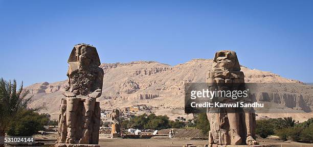 the colossi of memnon with the valley in background - colossi of memnon stock pictures, royalty-free photos & images