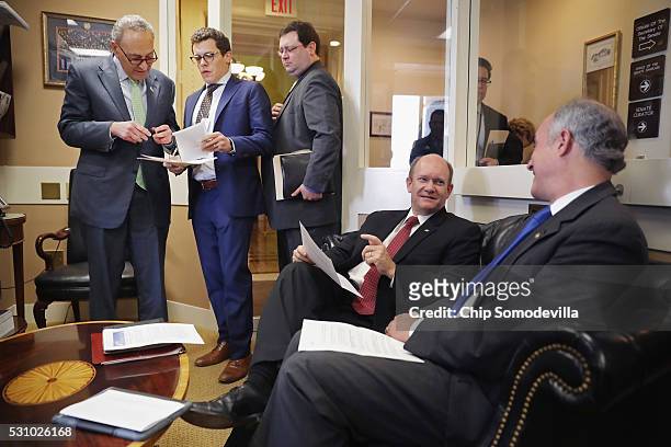 Sen. Charles Schumer talks with staff members as he and Sen. Chris Coons and Sen. Robert Casey prepare for a news conference following meetings...