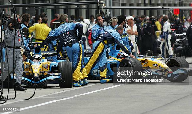 Fernando Alonso of Spain and Renault and his teammate Giancarlo Fisichella of Italy return to the pits to retire after one lap with all the others...