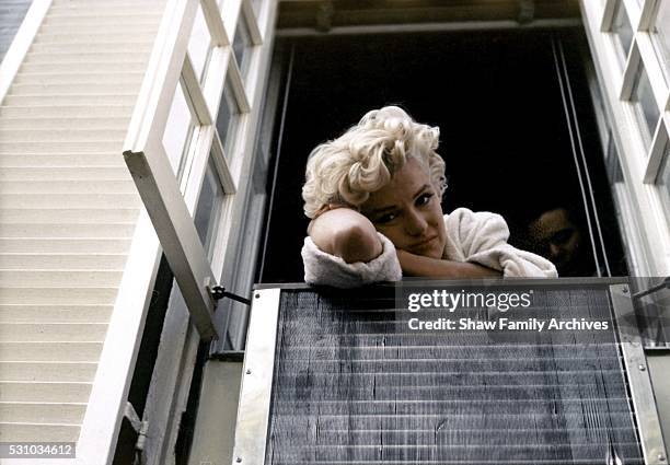 Marilyn Monroe leaning out of a window wearing a bathrobe in 1954 during the filming of "The Seven Year Itch" in New York, New York.