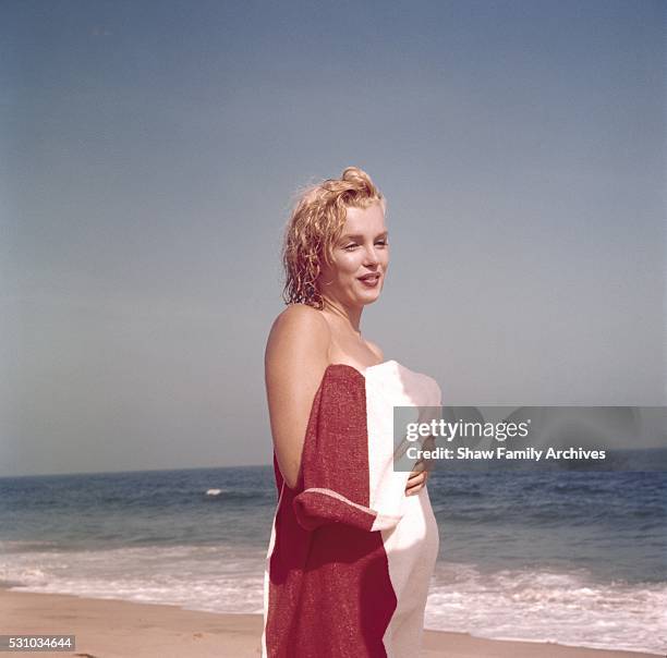 Marilyn Monroe stands on the beach holding a towel in 1957 in Amagansett, New York.