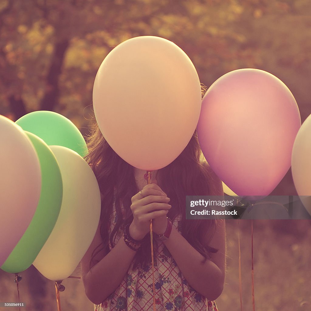 Girl hiding behind balloons