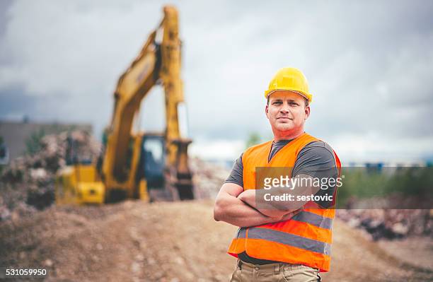 earth digger driver at construction site - graafmachine stockfoto's en -beelden