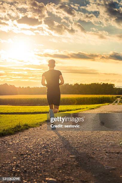 homme courir en direction du coucher de soleil - mens track photos et images de collection